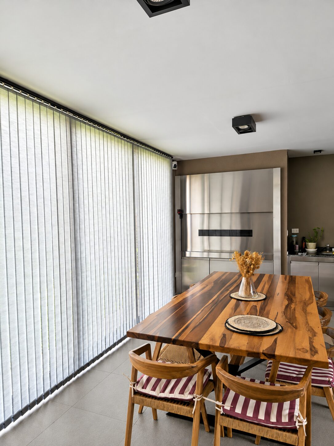 Bandas verticales South Beach en ventanal de quincho con mesa de madera